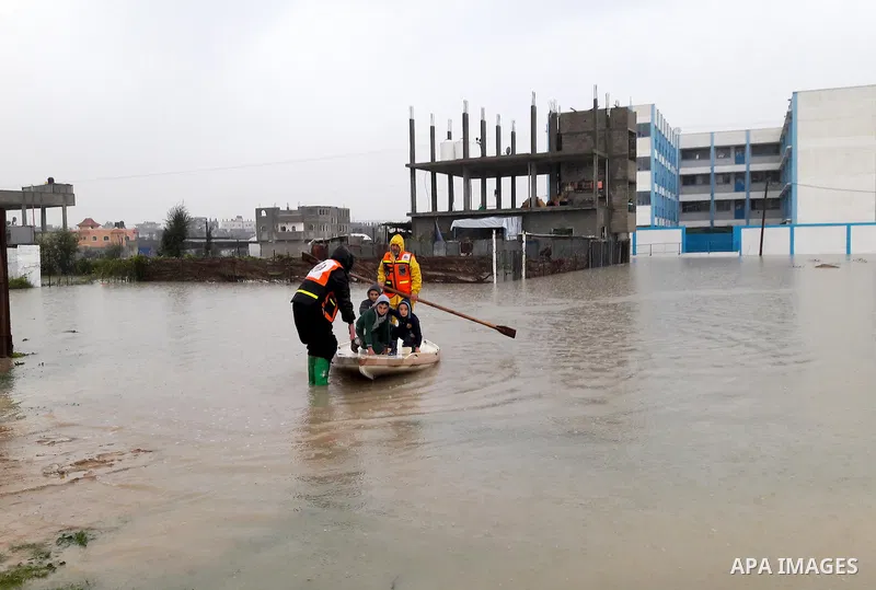 Palestinian Civil Defence workers use a stand-up kayak to evacuate people from a flooded area following heavy rainfall in the southern Gaza Strip town of Rafah on January 26, 2016. Photo by Abed Rahim Khatib