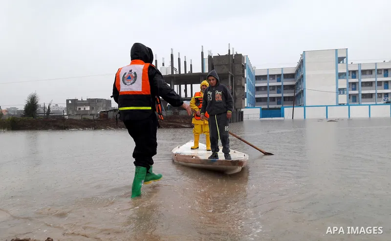 Palestinian Civil Defence workers use a stand-up kayak to evacuate people from a flooded area following heavy rainfall in the southern Gaza Strip town of Rafah on January 26, 2016. Photo by Abed Rahim Khatib