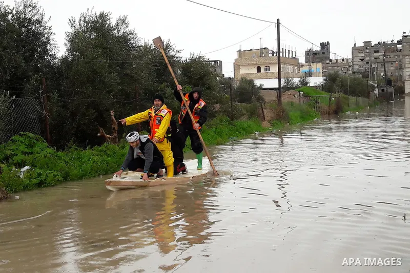 Palestinian Civil Defence workers use a stand-up kayak to evacuate people from a flooded area following heavy rainfall in the southern Gaza Strip town of Rafah on January 26, 2016. Photo by Abed Rahim Khatib