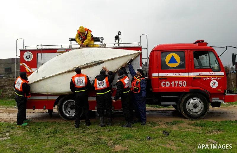 Palestinian Civil Defence workers use a stand-up kayak to evacuate people from a flooded area following heavy rainfall in the southern Gaza Strip town of Rafah on January 26, 2016. Photo by Abed Rahim Khatib