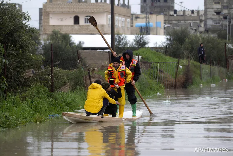 Palestinian Civil Defence workers use a stand-up kayak to evacuate people from a flooded area following heavy rainfall in the southern Gaza Strip town of Rafah on January 26, 2016. Photo by Abed Rahim Khatib