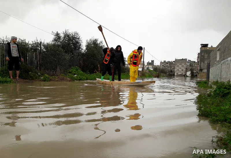 Palestinian Civil Defence workers use a stand-up kayak to evacuate people from a flooded area following heavy rainfall in the southern Gaza Strip town of Rafah on January 26, 2016. Photo by Abed Rahim Khatib