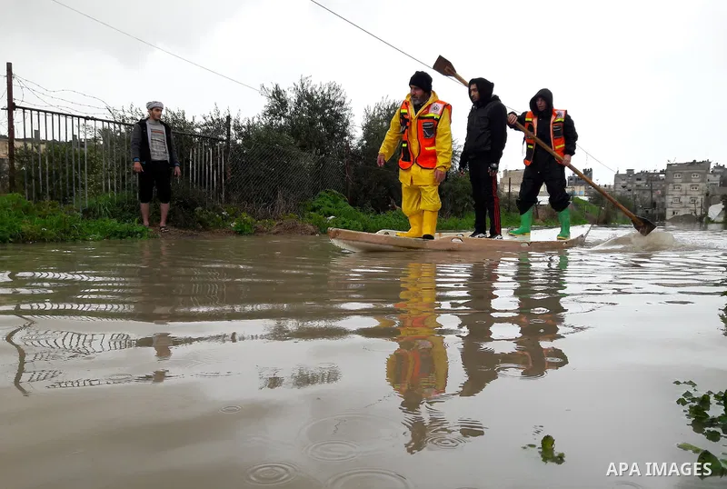 Palestinian Civil Defence workers use a stand-up kayak to evacuate people from a flooded area following heavy rainfall in the southern Gaza Strip town of Rafah on January 26, 2016. Photo by Abed Rahim Khatib