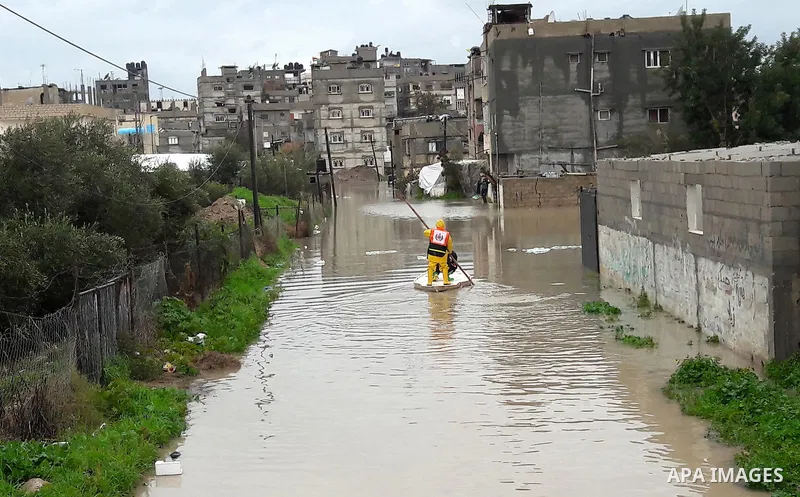Palestinian Civil Defence workers use a stand-up kayak to evacuate people from a flooded area following heavy rainfall in the southern Gaza Strip town of Rafah on January 26, 2016. Photo by Abed Rahim Khatib