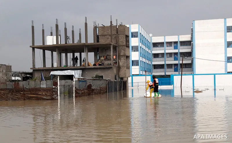 Palestinian Civil Defence workers use a stand-up kayak to evacuate people from a flooded area following heavy rainfall in the southern Gaza Strip town of Rafah on January 26, 2016. Photo by Abed Rahim Khatib