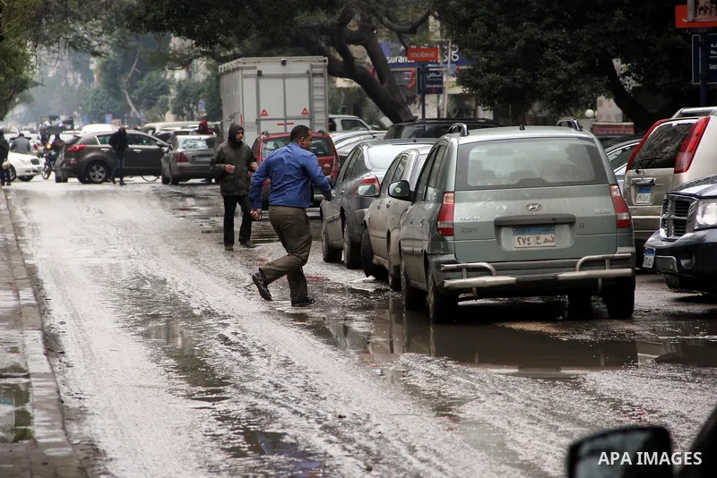 Egyptians walk in a street flooded by rain water, during a winter storm in Cairo, Egypt, on January 27, 2016. Photo by Amr Sayed