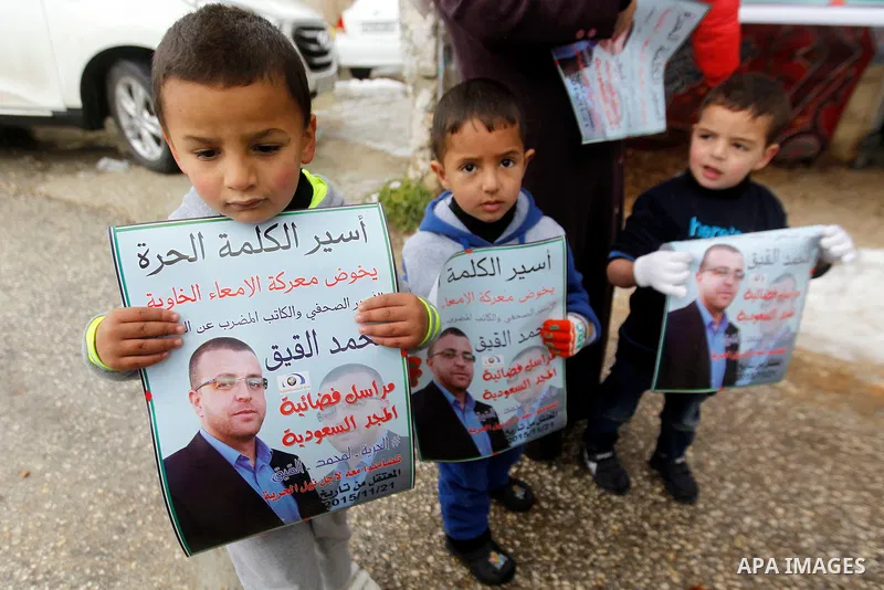 Palestinian children hold pictures of Palestinian journalist Mohammed al-Qiq who is on hunger strike in an Israeli jail for 64 days in front of a protest tent in the West Bank village of Dura on January 27, 2016. Qiq wen...