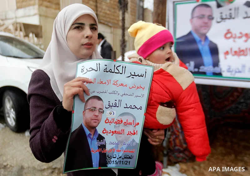 Fayha Shalash, the wife of Palestinian journalist Mohammed al-Qiq who is on hunger strike in an Israeli jail for 64 days holds her daughter in front of a protest tent in the West Bank village of Dura on January 27, 2016....