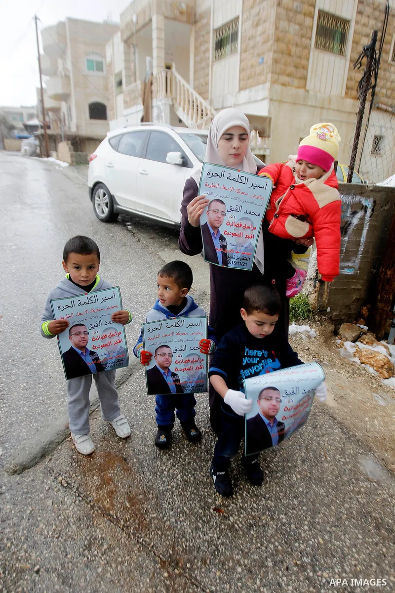 Fayha Shalash, the wife of Palestinian journalist Mohammed al-Qiq who is on hunger strike in an Israeli jail for 64 days holds her daughter in front of a protest tent in the West Bank village of Dura on January 27, 2016....
