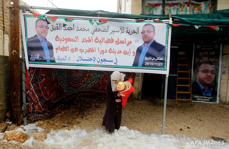 Fayha Shalash, the wife of Palestinian journalist Mohammed al-Qiq who is on hunger strike in an Israeli jail for 64 days holds her daughter in front of a protest tent in the West Bank village of Dura on January 27, 2016....