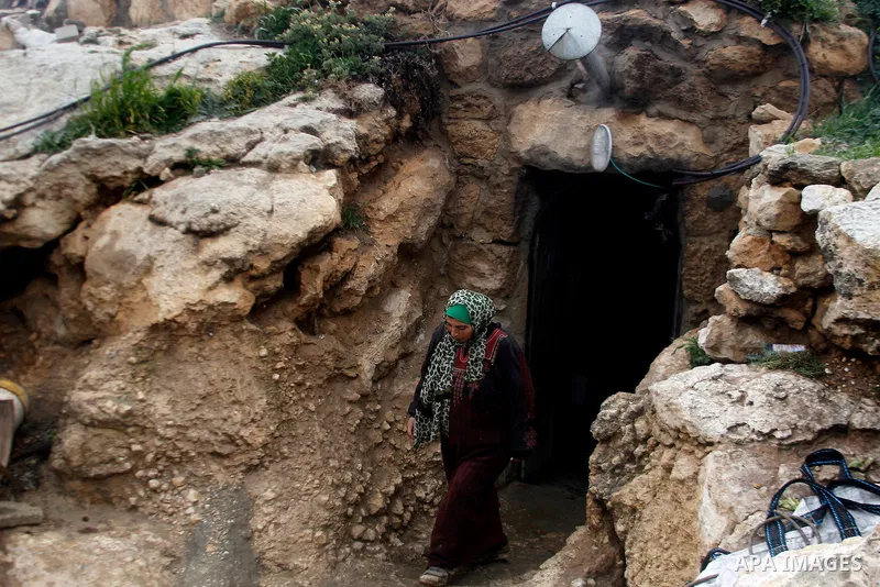 A Palestinian woman walks outside a cave she lives in, during a snow storm in West Bank village of Mufagara, south of Hebron January 27, 2016. Photo by Wisam Hashlamoun