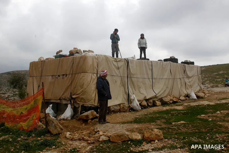 Palestinians remove rainwater from a tent during snow storm in West Bank Village of Mufagara, south of Hebron January 27, 2016. Photo by Wisam Hashlamoun