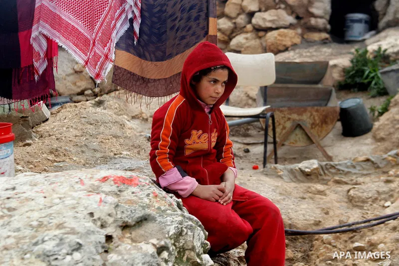 A Palestinian girl sits outside a cave she lives in, during a snow storm in West Bank village of Mufagara, south of Hebron January 27, 2016. Photo by Wisam Hashlamoun