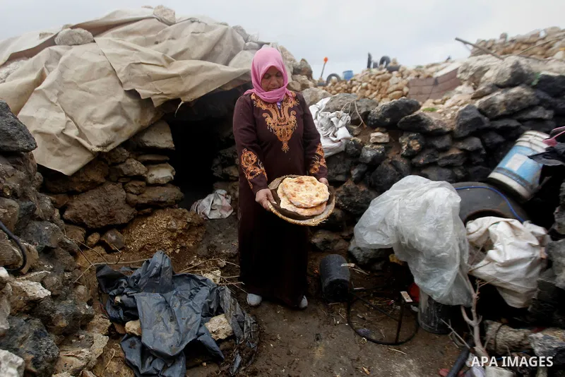 A Palestinian woman prepares a bread outside a cave she lives in, during a snow storm in West Bank village of Mufagara, south of Hebron January 27, 2016. Photo by Wisam Hashlamoun