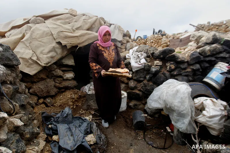 A Palestinian woman prepares a bread outside a cave she lives in, during a snow storm in West Bank village of Mufagara, south of Hebron January 27, 2016. Photo by Wisam Hashlamoun