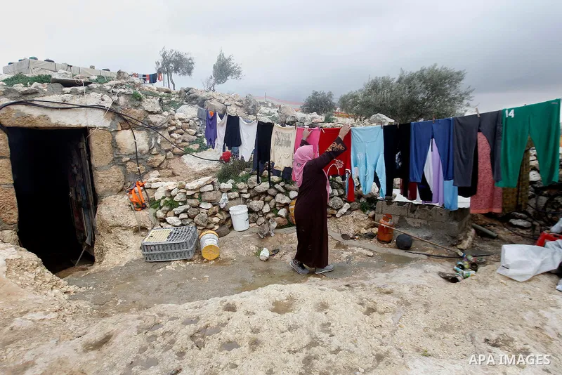 A Palestinian woman hangs laundry outside a cave they live in, during a snow storm in West Bank village of Mufagara, south of Hebron January 27, 2016. Photo by Wisam Hashlamoun