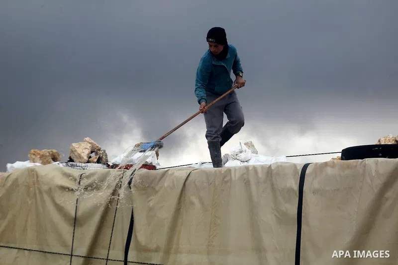 A Palestinian man removes rainwater from a tent during snow storm in West Bank Village of Mufagara, south of Hebron January 27, 2016. Photo by Wisam Hashlamoun