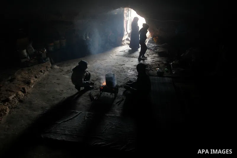 Palestinians warm themselves by a fire inside a cave they live in, during a snow storm in West Bank village of Mufagara, south of Hebron January 27, 2016. Photo by Wisam Hashlamoun