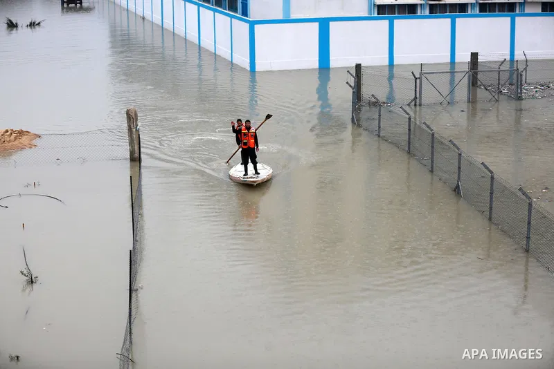 Palestinian Civil Defence workers use a stand-up kayak to evacuate people from a flooded area following heavy rainfall in Rafah in the southern Gaza Strip January 27, 2016. Photo by Yasser Qudih