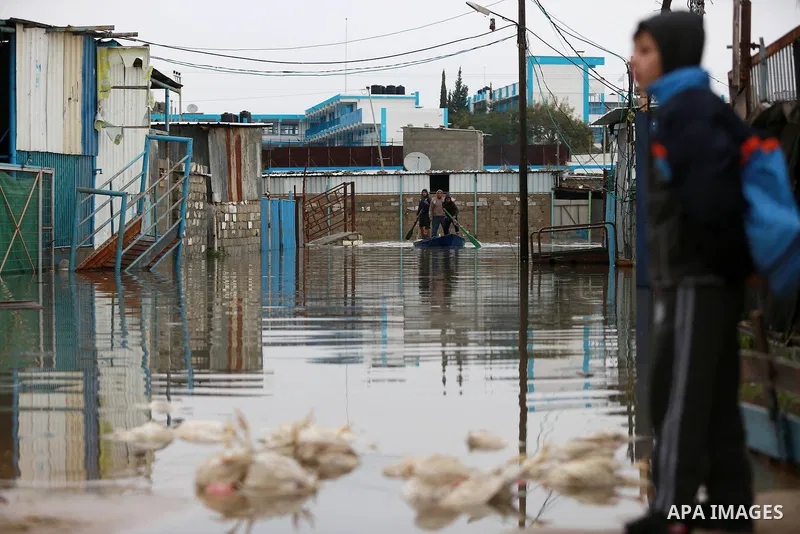 Palestinians paddle a boat in flood waters as they make their way to their flooded chicken farm during a winter storm in Rafah in the southern Gaza Strip January 27, 2016. Photo by Yasser Qudih