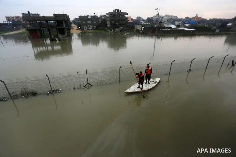 Palestinian Civil Defence workers use a stand-up kayak to evacuate people from a flooded area following heavy rainfall in Rafah in the southern Gaza Strip January 27, 2016. Photo by Yasser Qudih