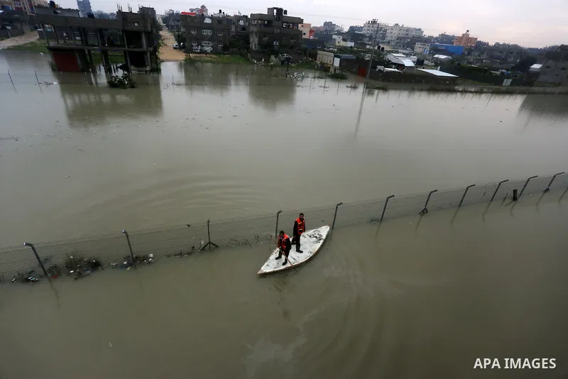 Palestinian Civil Defence workers use a stand-up kayak to evacuate people from a flooded area following heavy rainfall in Rafah in the southern Gaza Strip January 27, 2016. Photo by Yasser Qudih