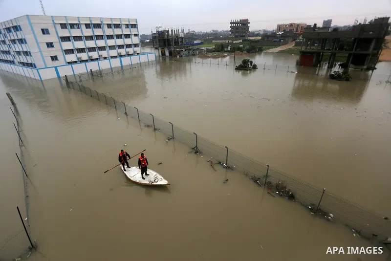 Palestinian Civil Defence workers use a stand-up kayak to evacuate people from a flooded area following heavy rainfall in Rafah in the southern Gaza Strip January 27, 2016. Photo by Yasser Qudih