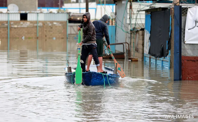 Palestinians paddle a boat in flood waters as they make their way to their flooded chicken farm during a winter storm in Rafah in the southern Gaza Strip January 27, 2016. Photo by Yasser Qudih
