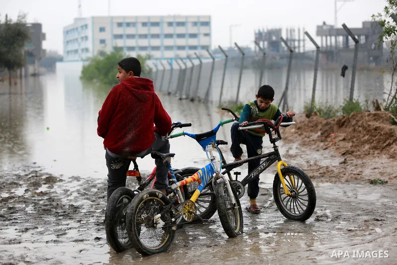 Palestinian boys ride a bicycle during a winter storm in Rafah in the southern Gaza Strip January 27, 2016. Photo by Yasser Qudih