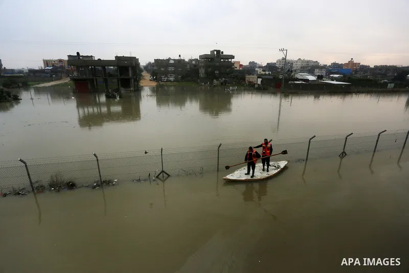 Palestinian Civil Defence workers use a stand-up kayak to evacuate people from a flooded area following heavy rainfall in Rafah in the southern Gaza Strip January 27, 2016. Photo by Yasser Qudih