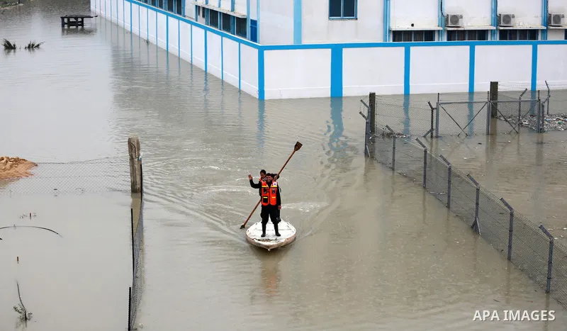 Palestinian Civil Defence workers use a stand-up kayak to evacuate people from a flooded area following heavy rainfall in Rafah in the southern Gaza Strip January 27, 2016. Photo by Yasser Qudih