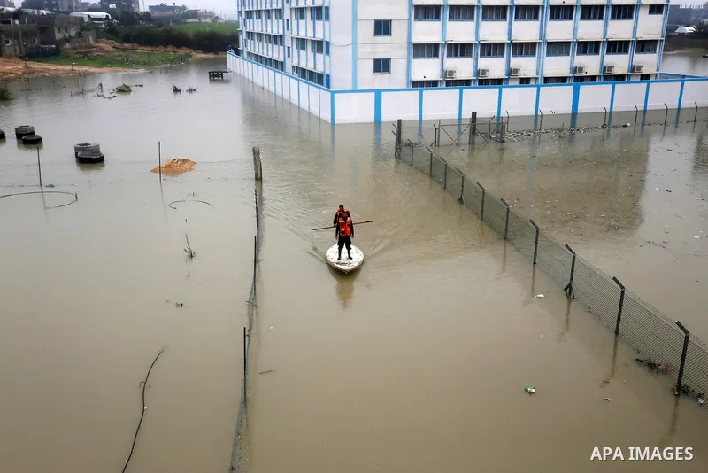 Palestinian Civil Defence workers use a stand-up kayak to evacuate people from a flooded area following heavy rainfall in Rafah in the southern Gaza Strip January 27, 2016. Photo by Yasser Qudih