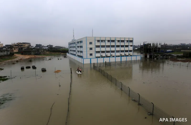 Palestinian Civil Defence workers use a stand-up kayak to evacuate people from a flooded area following heavy rainfall in Rafah in the southern Gaza Strip January 27, 2016. Photo by Yasser Qudih