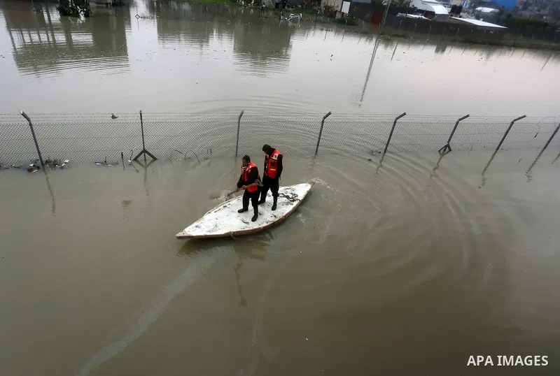 Palestinian Civil Defence workers use a stand-up kayak to evacuate people from a flooded area following heavy rainfall in Rafah in the southern Gaza Strip January 27, 2016. Photo by Yasser Qudih