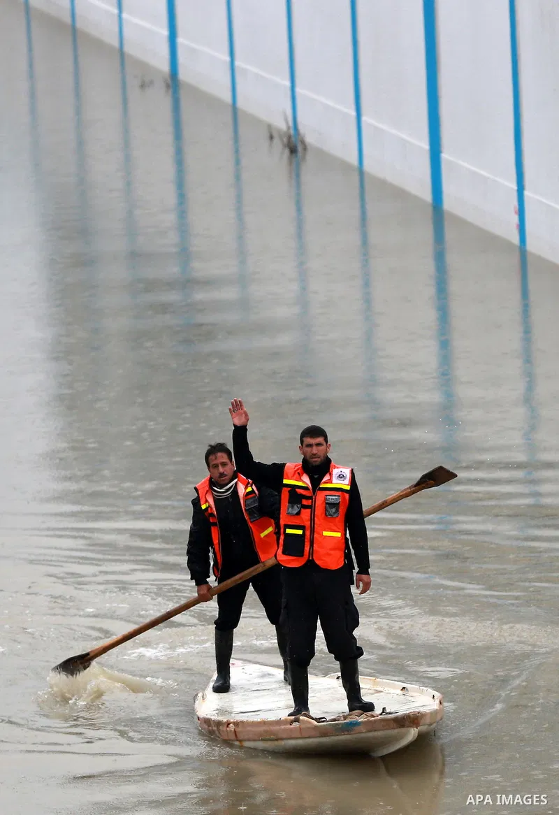 Palestinian Civil Defence workers use a stand-up kayak to evacuate people from a flooded area following heavy rainfall in Rafah in the southern Gaza Strip January 27, 2016. Photo by Yasser Qudih