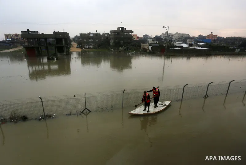 Palestinian Civil Defence workers use a stand-up kayak to evacuate people from a flooded area following heavy rainfall in Rafah in the southern Gaza Strip January 27, 2016. Photo by Yasser Qudih