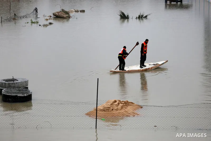 Palestinian Civil Defence workers use a stand-up kayak to evacuate people from a flooded area following heavy rainfall in Rafah in the southern Gaza Strip January 27, 2016. Photo by Yasser Qudih