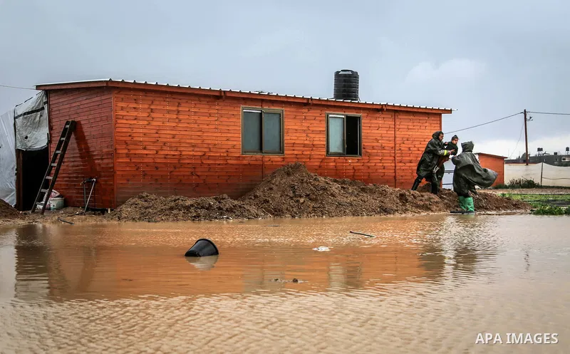 A picture taken on January 25, 2016 shows Members of Palestinian Civil Defence evacuation children, whose families house was destroyed during the 2014 war, after rain waters flooded their families shelter, in Khan Younis...