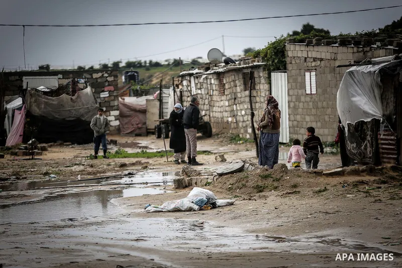 A picture taken on January 25, 2016 shows Palestinians gather at a flooded road following heavy rainfall, in Khan Younis in the southern Gaza Strip. Photo by Mohammed Dahman