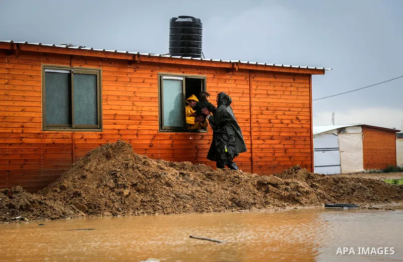 A picture taken on January 25, 2016 shows Members of Palestinian Civil Defence evacuation children, whose families house was destroyed during the 2014 war, after rain waters flooded their families shelter, in Khan Younis...