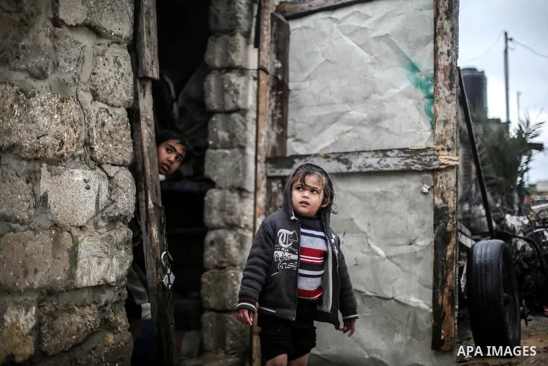 A picture taken on January 25, 2016 shows A Palestinian girl stands on her family's doorstep looking at a flooded street following heavy rainfall in Khan Younis in the southern Gaza Strip. Photo by Mohammed Dahman