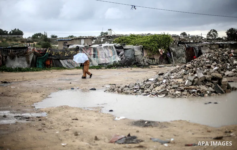 A picture taken on January 25, 2016 shows Palestinian children cross a flooded road following heavy rainfall, in Khan Younis in the southern Gaza Strip. Photo by Mohammed Dahman