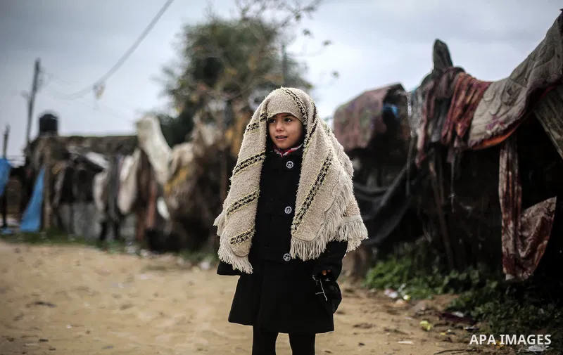 A picture taken on January 25, 2016 shows A Palestinian girl looks on a flooded street following heavy rainfall in Khan Younis in the southern Gaza Strip. Photo by Mohammed Dahman