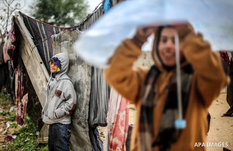 A picture taken on January 25, 2016 shows Palestinian children play outside their family's house following heavy rainfall in Khan Younis in the southern Gaza Strip. Photo by Mohammed Dahman