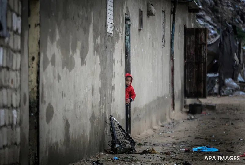 A picture taken on January 25, 2016 shows A Palestinian girl stands on her family's doorstep looking at a flooded street following heavy rainfall in Khan Younis in the southern Gaza Strip. Photo by Mohammed Dahman