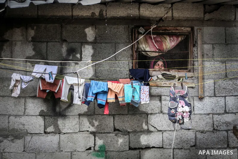 A picture taken on January 25, 2016 shows A Palestinian woman looks out a window on a flooded street following heavy rainfall in Khan Younis in the southern Gaza Strip. Photo by Mohammed Dahman