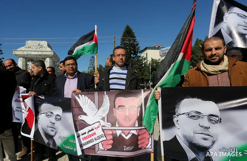 Palestinian Journalists hold pictures of journalist Mohammed al-Qeq, who has been on a hunger strike in an Israeli jail for 65 days, during a protest to show solidarity with him, in Gaza city January 28, 2016. Qeq went o...