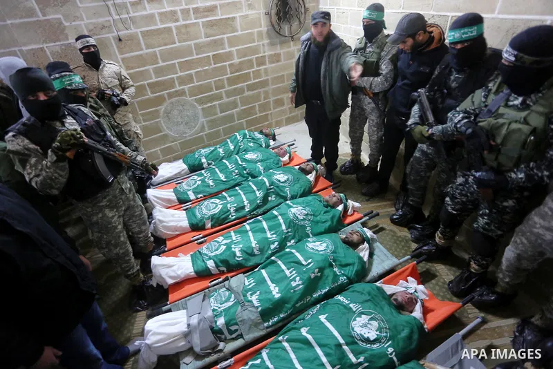 Palestinian members of Ezzedeen al-Qassam, the armed wing of Hamas movement, sit next to the bodies of Palestinian Hamas militants whom killed after a tunnel, built for fighting Israel, collapsed in the Gaza Strip, durin...