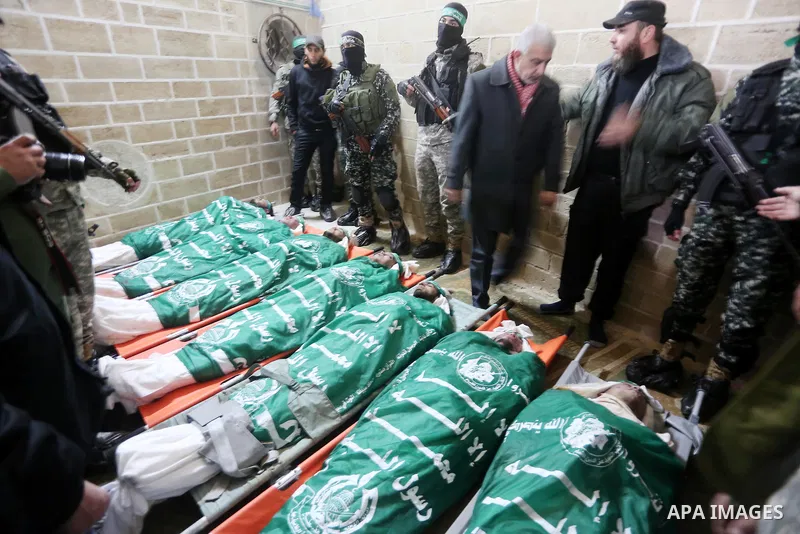 Palestinian members of Ezzedeen al-Qassam, the armed wing of Hamas movement, sit next to the bodies of Palestinian Hamas militants whom killed after a tunnel, built for fighting Israel, collapsed in the Gaza Strip, durin...