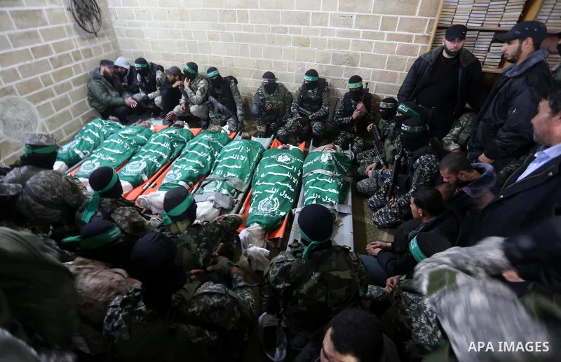 Palestinian members of Ezzedeen al-Qassam, the armed wing of Hamas movement, sit next to the bodies of Palestinian Hamas militants whom killed after a tunnel, built for fighting Israel, collapsed in the Gaza Strip, durin...